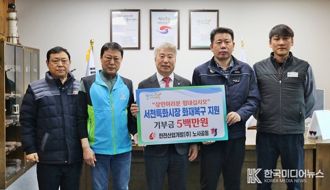 =사진설명 ; 한전산업개발 함흥규 대표(중앙)와 오일환 상인회장(왼쪽 두 번째) 및 양측 관계자들이 서천특화시장 화재복구 기부금 전달 후 기념 사진 촬영에 응하고 있다.