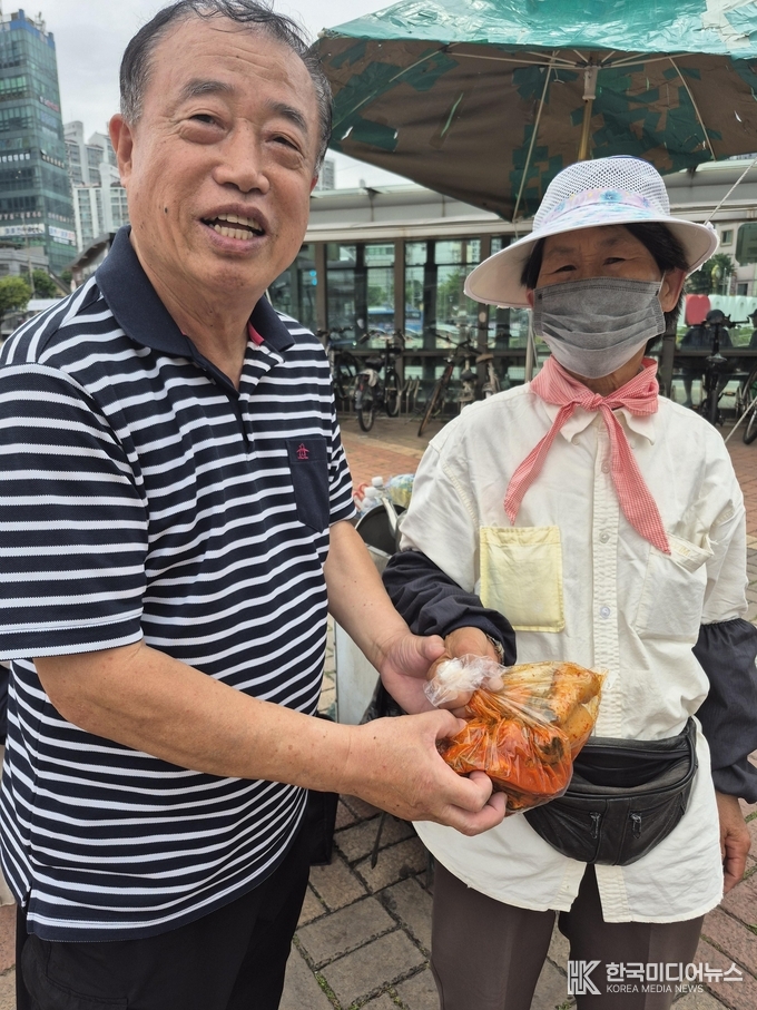 = =사진설명 ; 조명탄 목사가 서은영대표가 기부한 갓 김치를 나누워 주고있다.